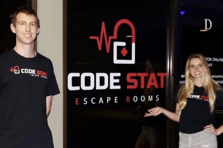 Ryan Rohde (left) and Addison Morris (right) pose in front of their newly opened escape room called Code Stat .