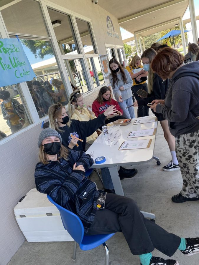 Oct. 19 2021, during lunch Senior Grace Hurguy poses for camera while  passing out surveys in exchange for Popsicles for the wellness center with other wellness leaders.