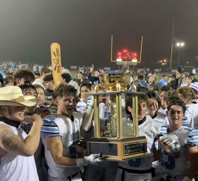 Varsity football players (left to right) Payton Hoff, Jackson Geier, Manny Mendez and Kaiden Brunkan pose for a photo holding up their victory trophy. 