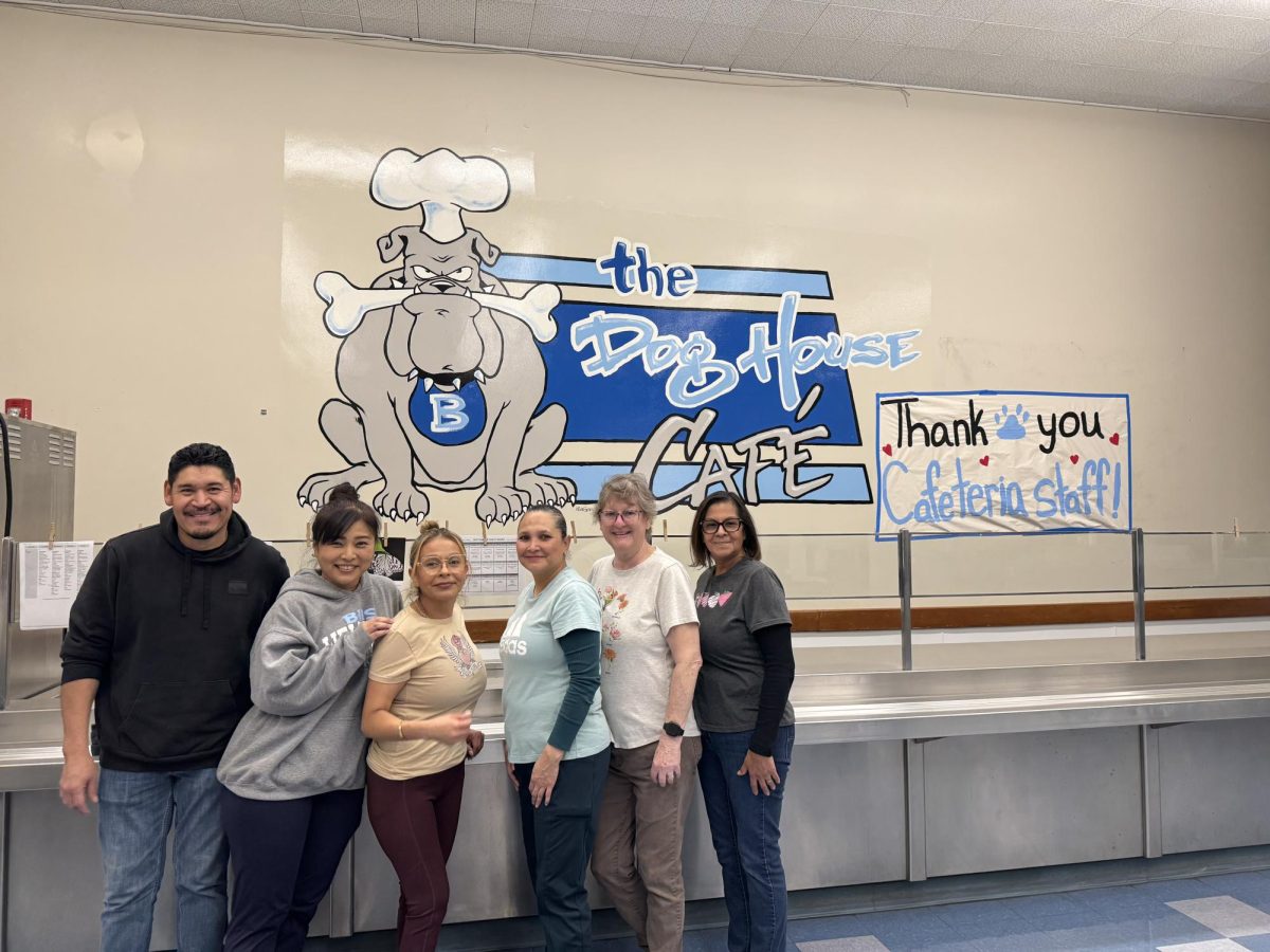 The cafeteria poses in front of the cafeteria mural. (From left to right) Ulises Hernandez Baltazar, Yukari Bell, Susanna Gomez, Sarah E Ortiz, Kimberly Hunter, Angie Marin